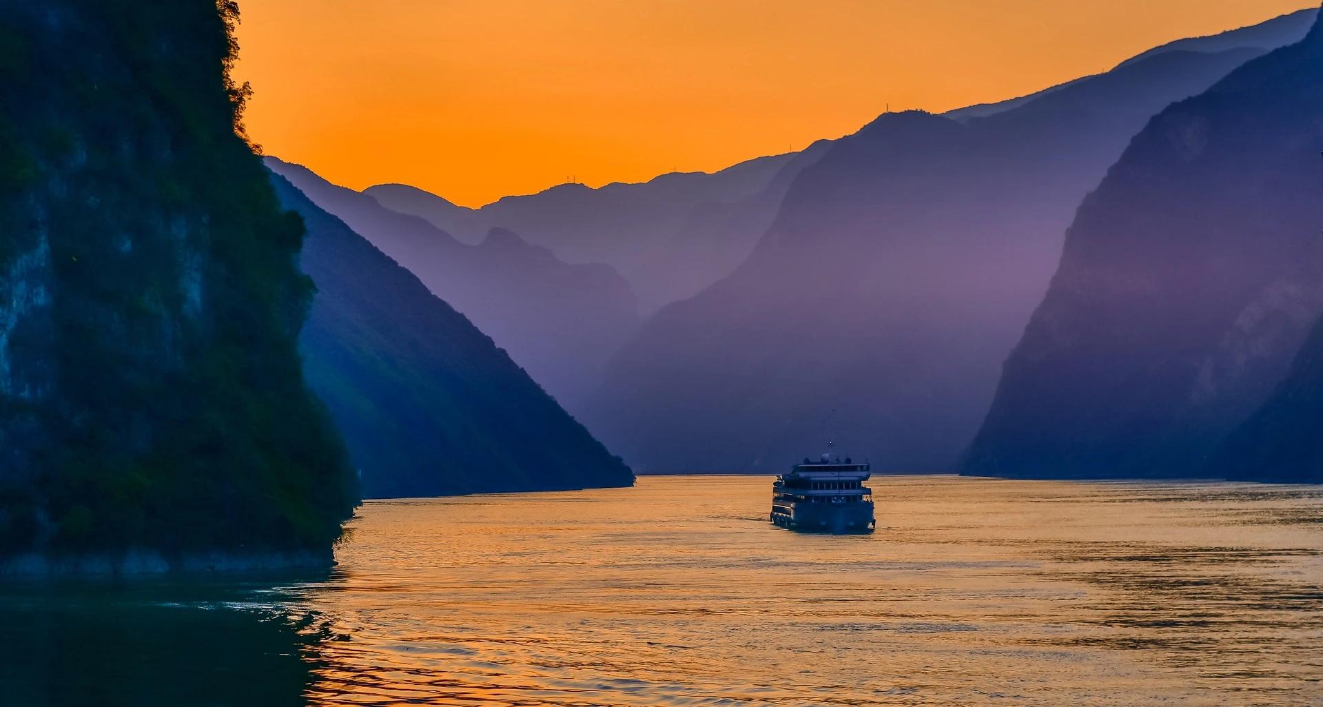 A cruise ship on the Yangtze River among misty gorges at sunset