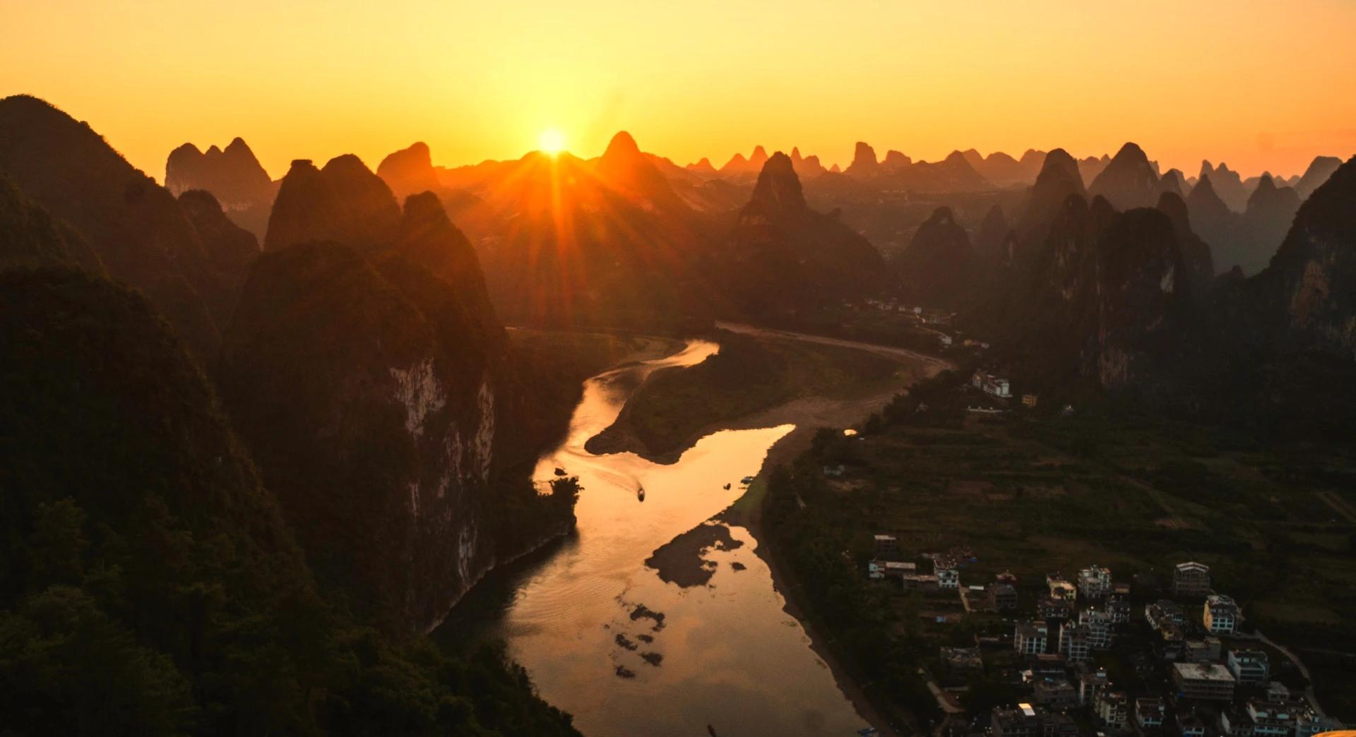 A traditional boat cruising the Li River among karst mountains at sunset